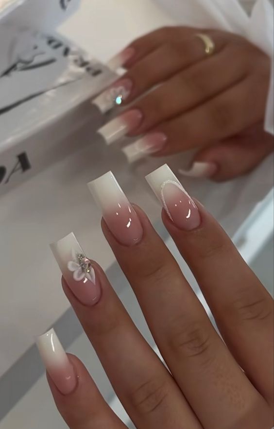 Sophisticated Ombre Nail Design with Floral Accents and Gem Detail.