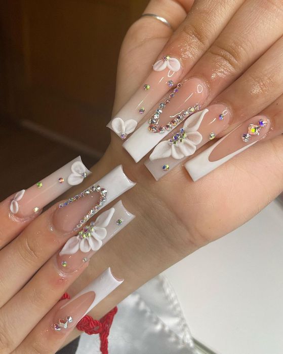 Sophisticated and Playful: Elegant Acrylic Nail Design with 3D Floral Accents and Rhinestones.