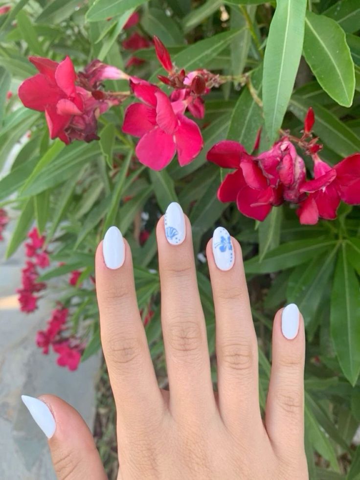 Chic Summer Elegance: Intricate Blue Designs on White Nails Against Vibrant Floral Backdrop.