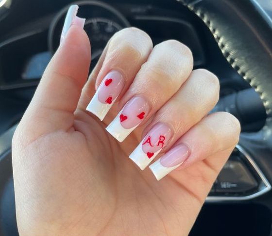 Charming French Tip Nail Design with Red Hearts and Personal Touches.