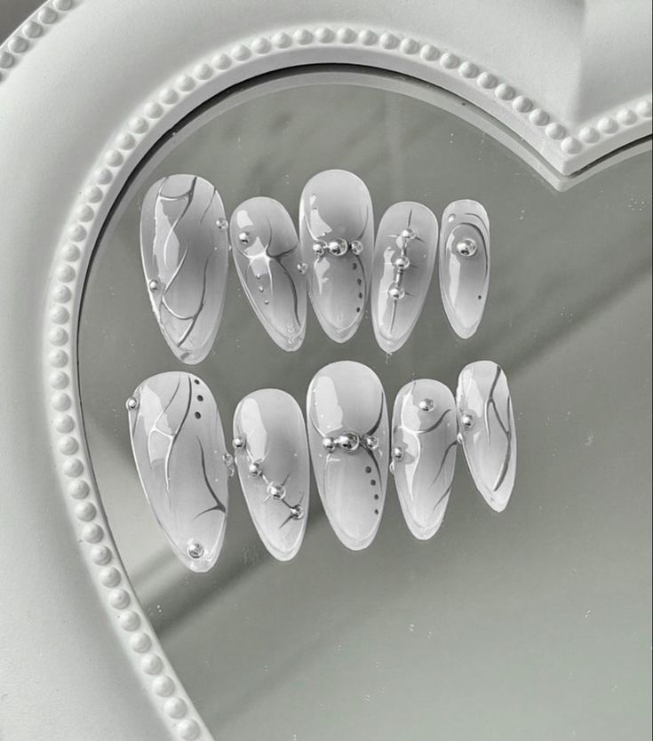 Chic Elegant Nail Design with Soft White Base, Intricate Linework, and Pearl Accents.