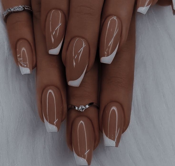 Sophisticated Nail Design: Soft Nude Tones with Crisp White Tips and Artistic Flair.