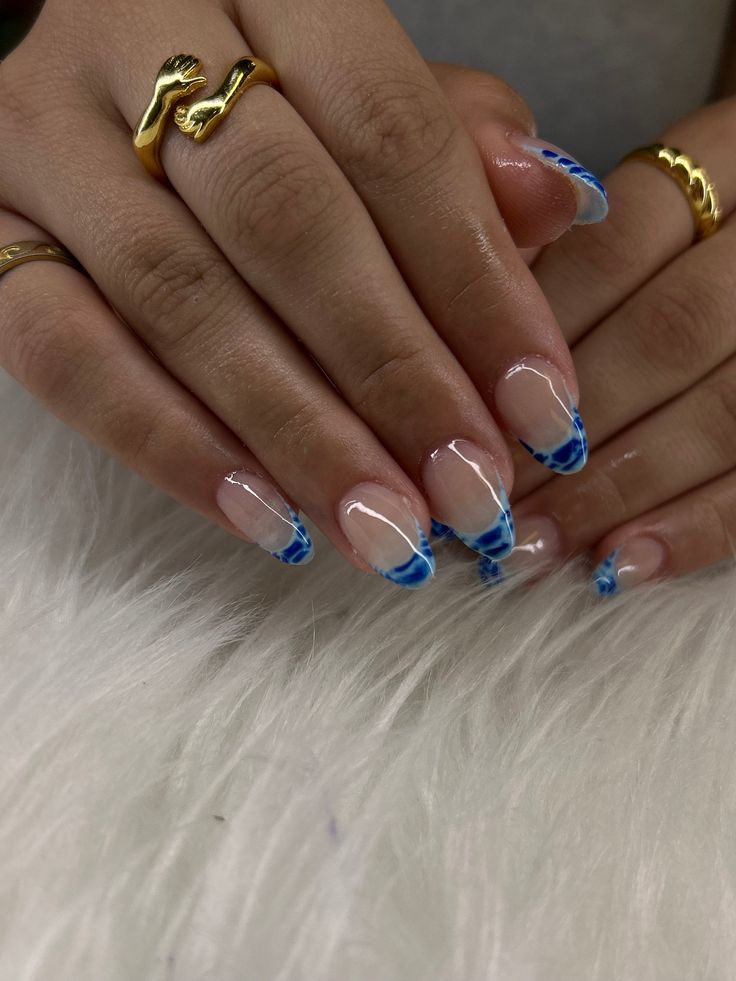 Trendy Elegant Nail Design: Clear and Soft Pink Polish with Blue Tips and Wave Pattern Accents.