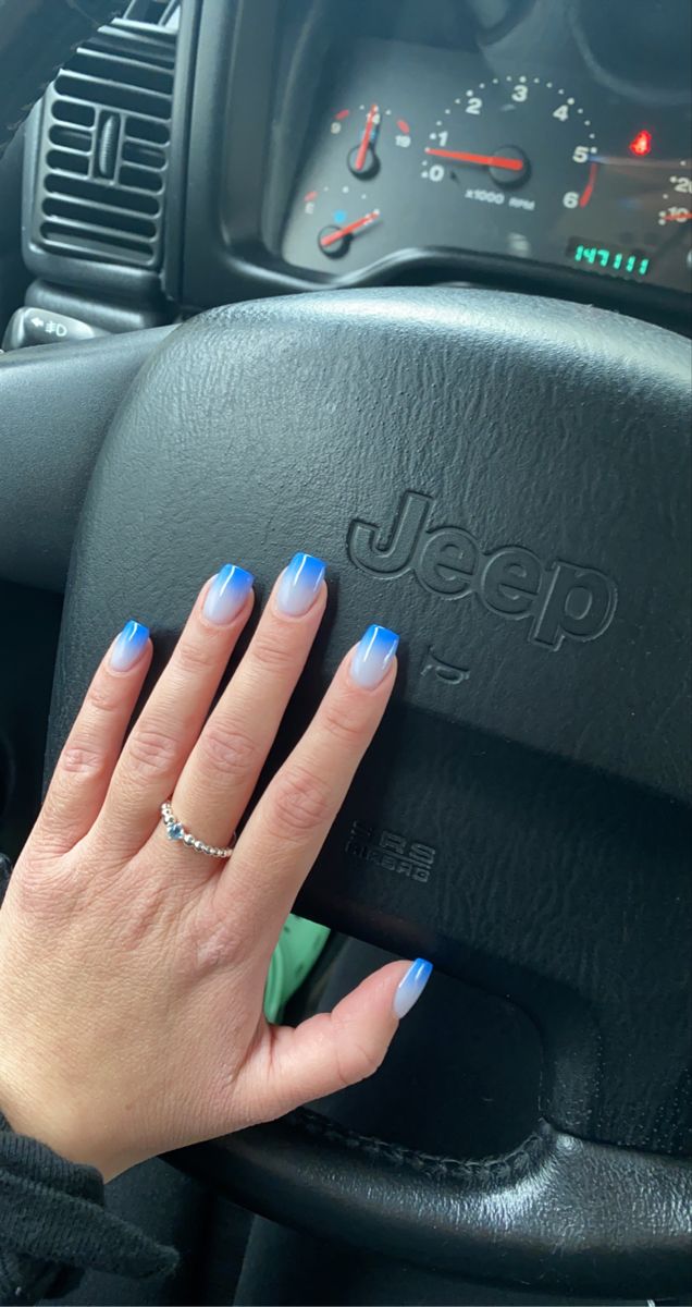 Chic Ombre Nail Design in Soft to Dark Blue with Elegant Silver Ring Against Steering Wheel Backdrop