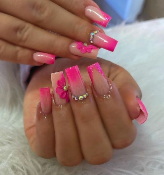 Playful Pink Ombre Nails with Floral Embellishments and Sparkling Rhinestones