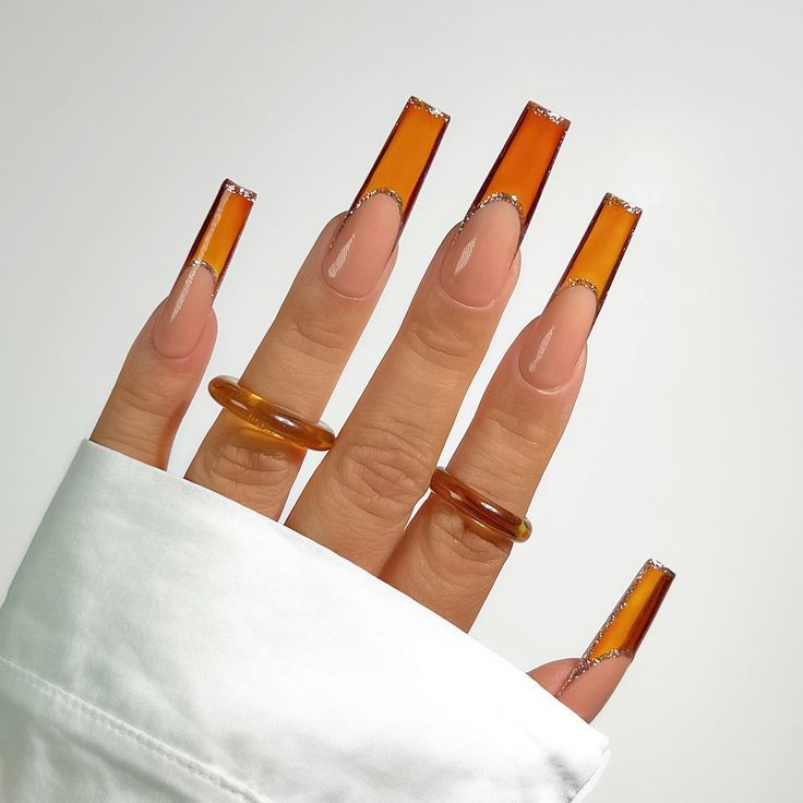 Chic Amber-Inspired Long Nails with Glossy Gradient Tips and Complementary Rings.