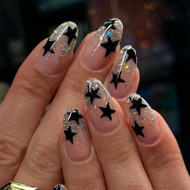 Celestial Chic: Transparent Base Nail Art with Silver Glitter and Bold Black Star Tips