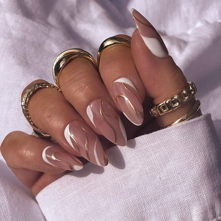 Chic Nude and White Swirl Nail Design with Sophisticated Gold Accents.