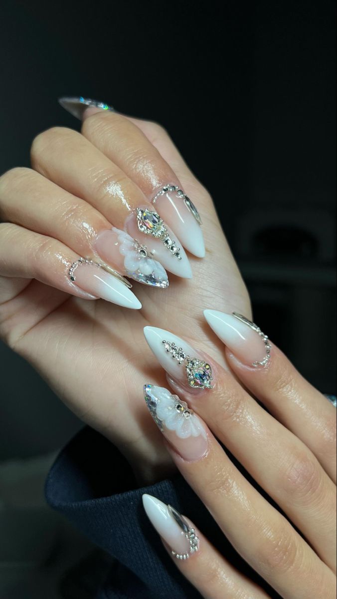 Luxurious Stiletto-Almond Nail Design with Deep White Polish, Translucent Accents, and Gem Adornments.