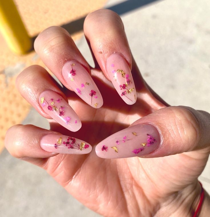 Elegant Stiletto Floral Nail Design with Soft Nude Base and Vibrant Pink-Gold Accents