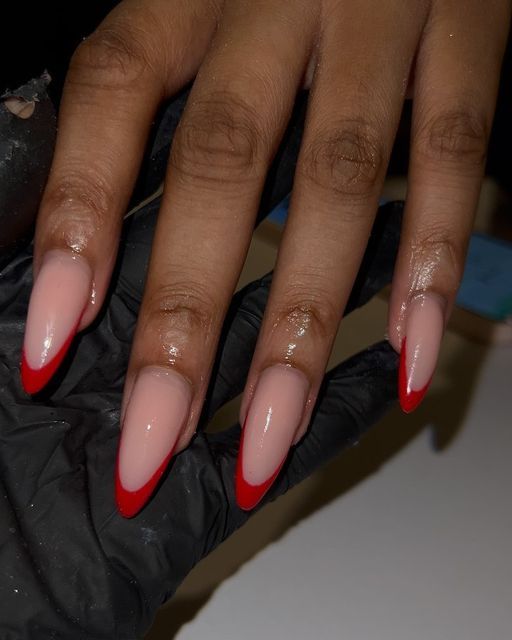 Elegant Almond-Shaped Nail Design with Bold Red Tips on Soft Nude Base.