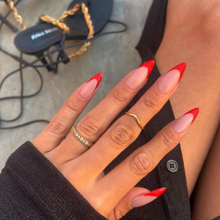 Elegant Ombre Red-Tipped Almond Nails with Minimalist Rings for a Bold, Sophisticated Look.