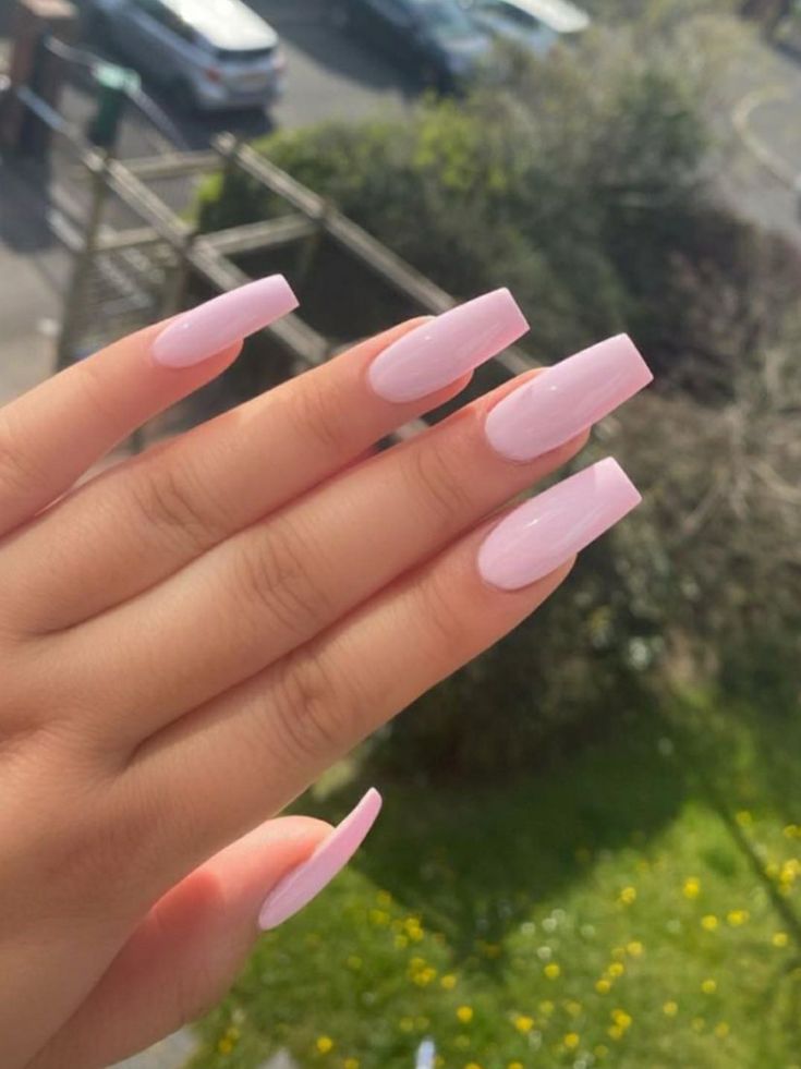 Elegant Soft Pink Square Nails with Glossy Finish Against Lush Green Background