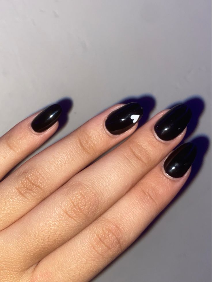 Chic Glossy Black Almond-Shaped Nails with Playful White Heart Accent.