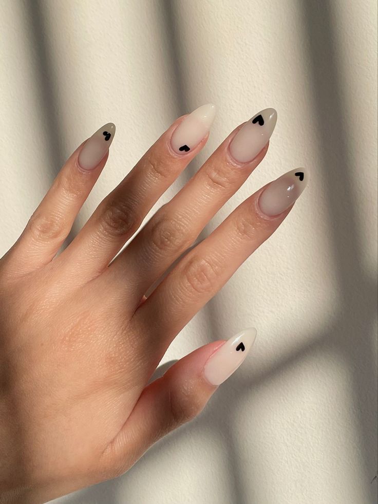 Chic Nail Design: Soft Nude and Blush Tones with Playful Black Heart Accents