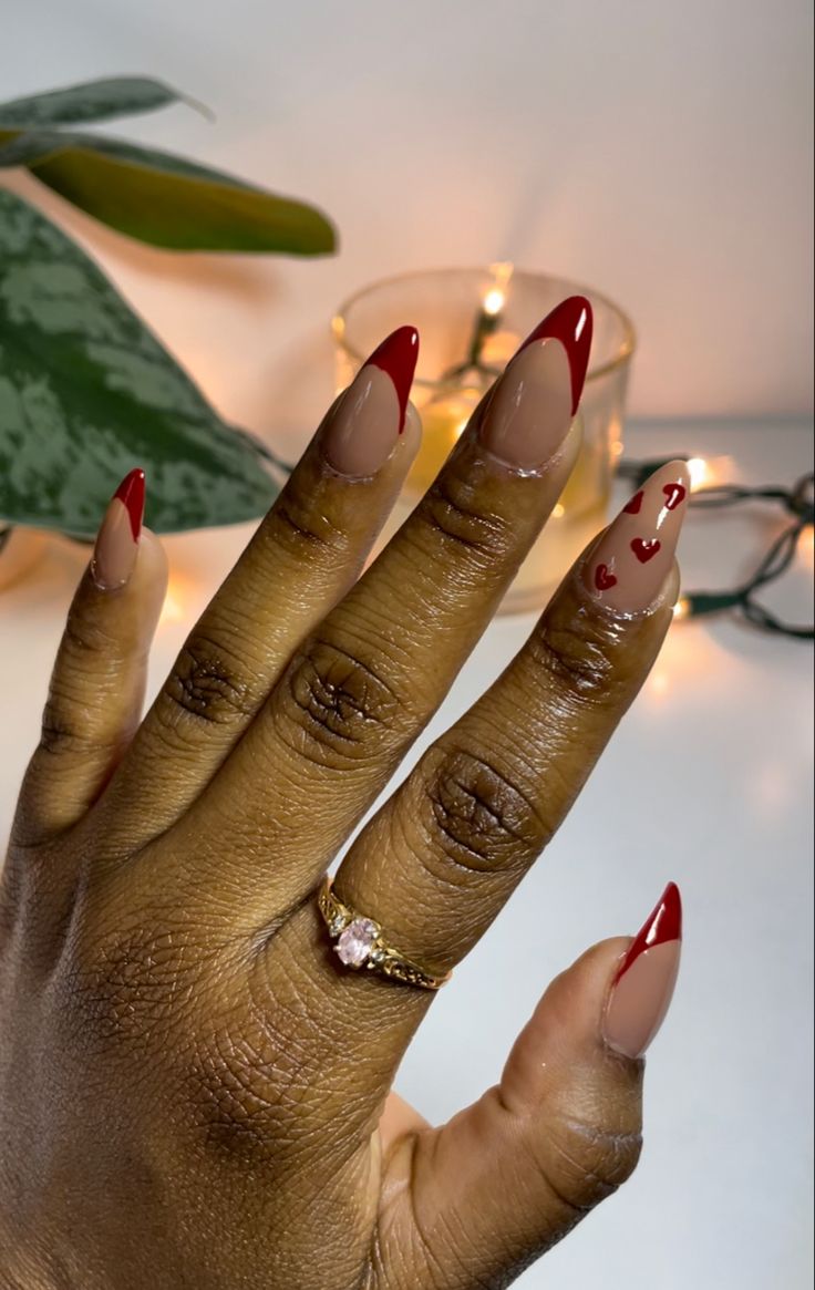 Chic Nude and Red Nail Design with Heart Accents and Classic French Tips.