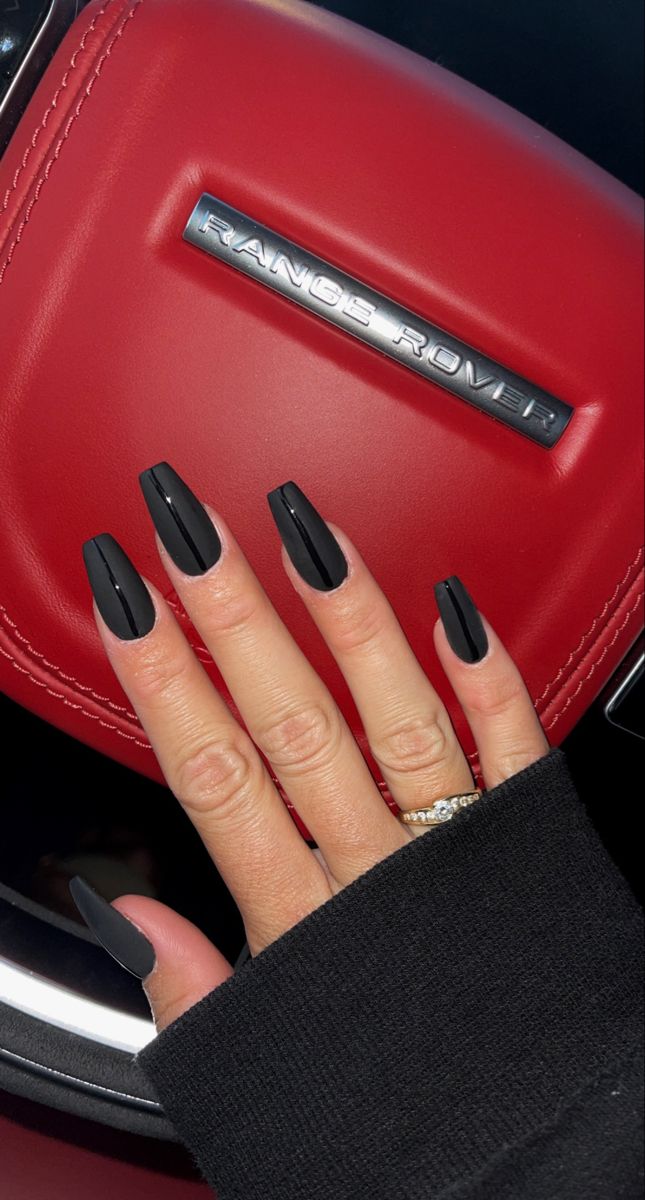 Sophisticated Black Acrylic Nails Create an Edgy Contrast with Luxurious Red Upholstery.