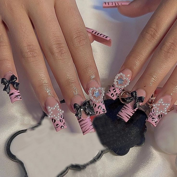 Chic Pastel Pink and Black Nail Design with Playful Embellishments and Trendy Patterns.