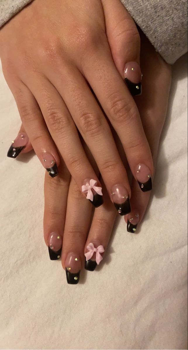 Chic Black Tip and Soft Pink Nail Design with Gems and Bows for a Bold, Feminine Statement.