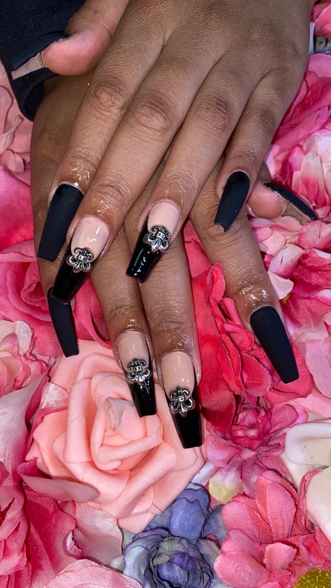 Chic Black and Nude Nail Design with Glossy Tips and Metallic Embellishments.