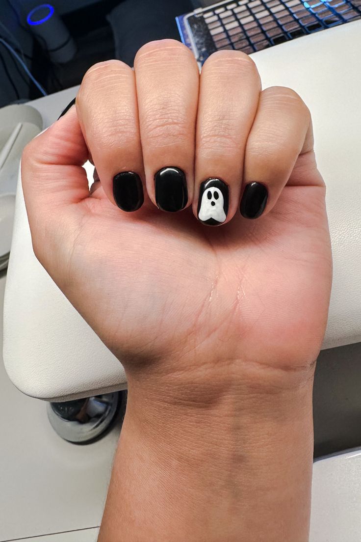 Stylish Black and White Nail Design with Playful Ghost Accent for Halloween.