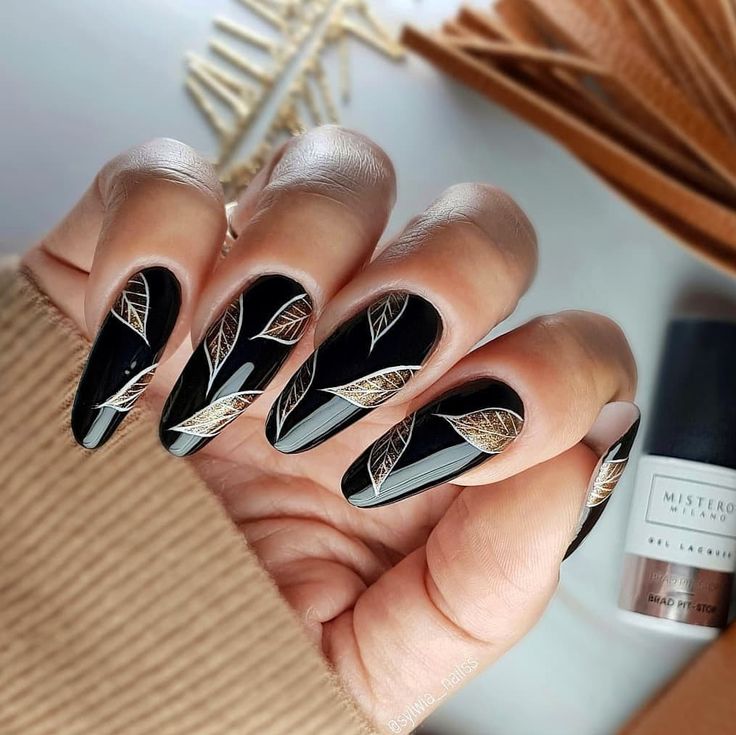 Sophisticated Black Base Nail Art with Intricate Leaf Designs and Golden Accents.