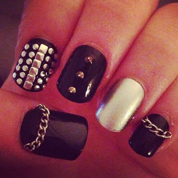 Bold Matte Black and Metallic Nail Design with Studs, Chains, and Gems for an Edgy Statement Look.