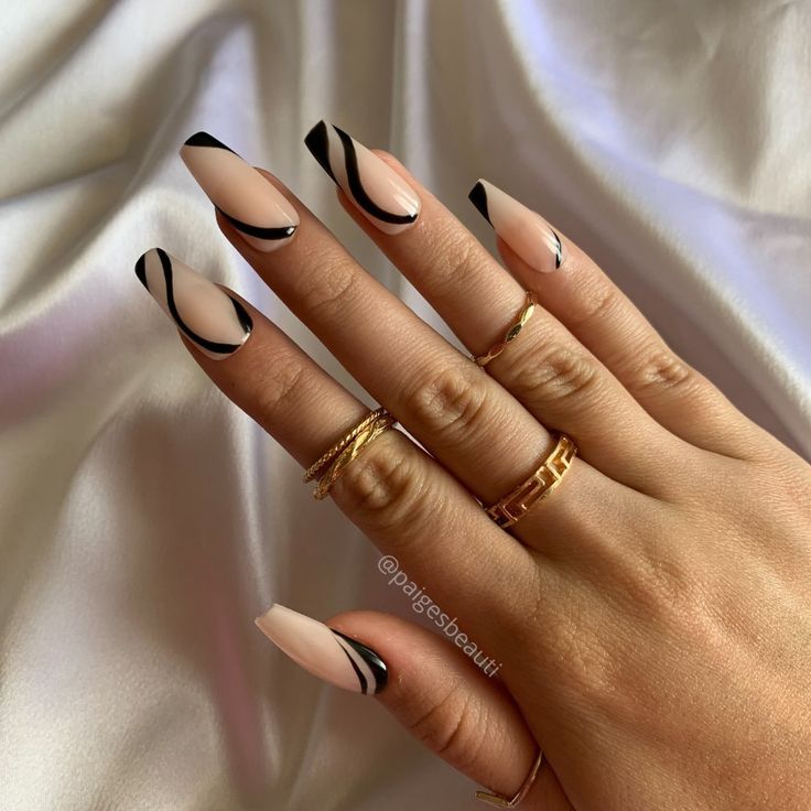 Sophisticated Nail Art: Soft Nude Base with Bold Black Accents and Chic Gold Rings