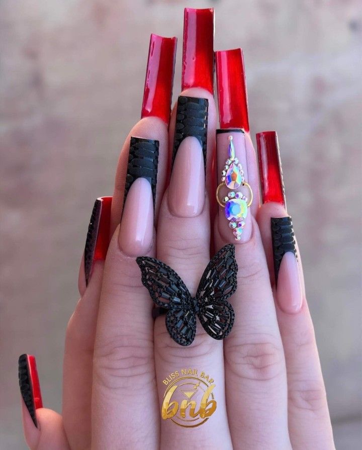 Elegant and Edgy Nail Design: Long Tips with Glossy Red, Black Accents, and Sparkling Gem Details.