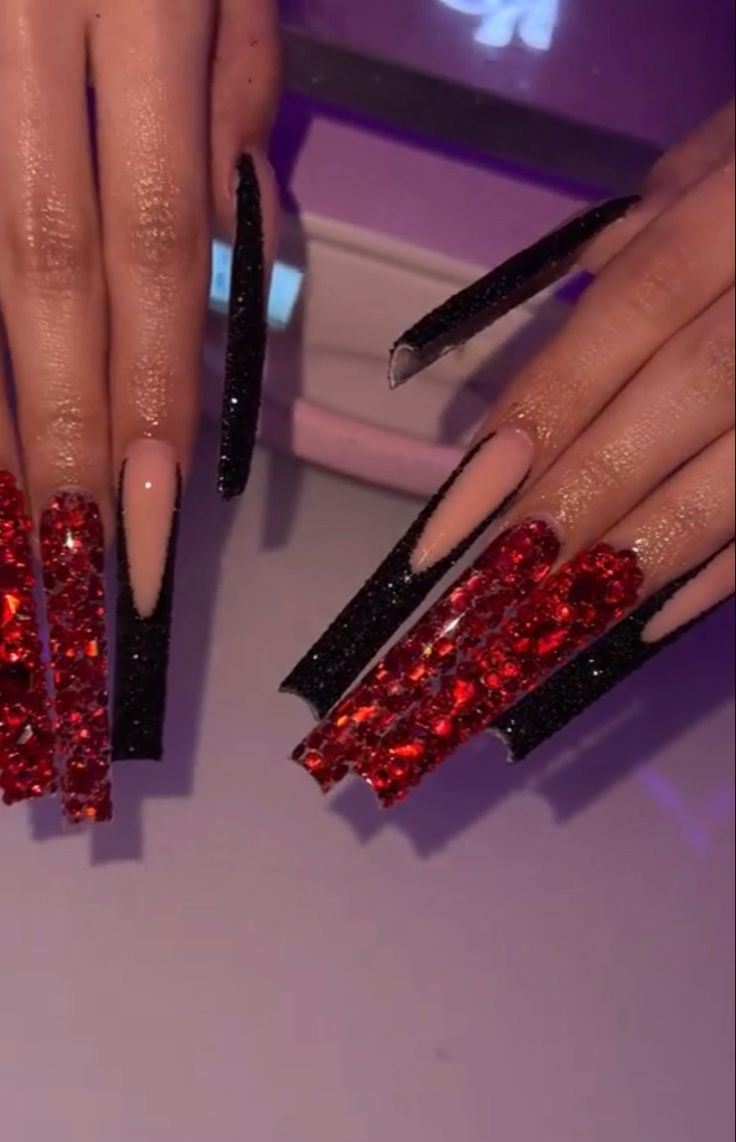 Elegant Stiletto Nail Design with Black Glitter, Red Rhinestones, and Sophisticated Nude Base.