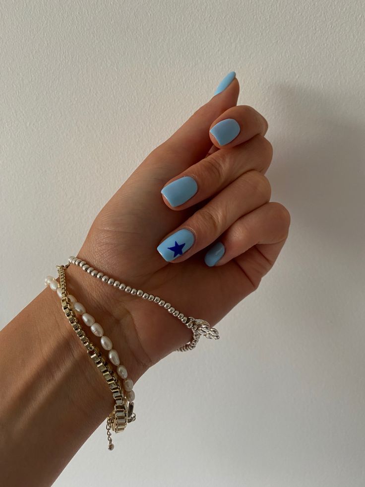 Elegant Soft Blue Matte Nail Design with Playful Star Accent and Stylish Bracelets.