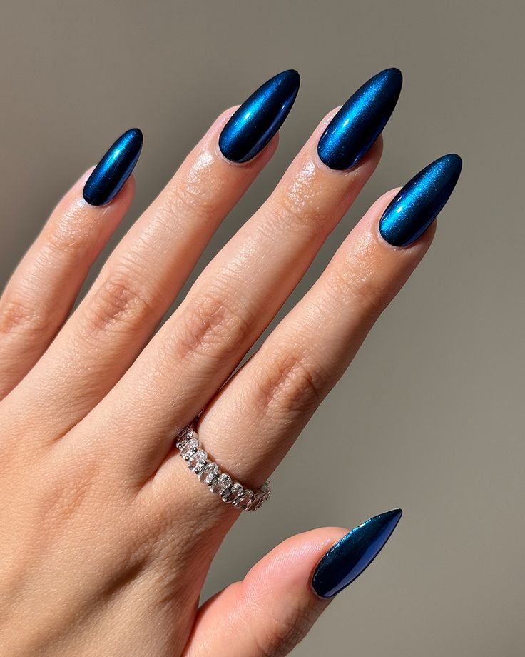 Elegant Navy Blue Shimmer Nails Enhanced by a Delicate Ring.