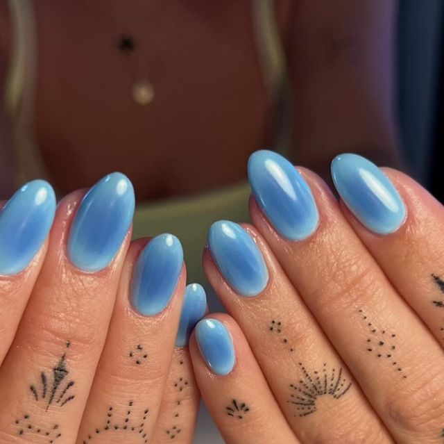 Stunning Ombre Blue Nails with Intricate Black Tattoos for a Vibrant, Elegant Look.