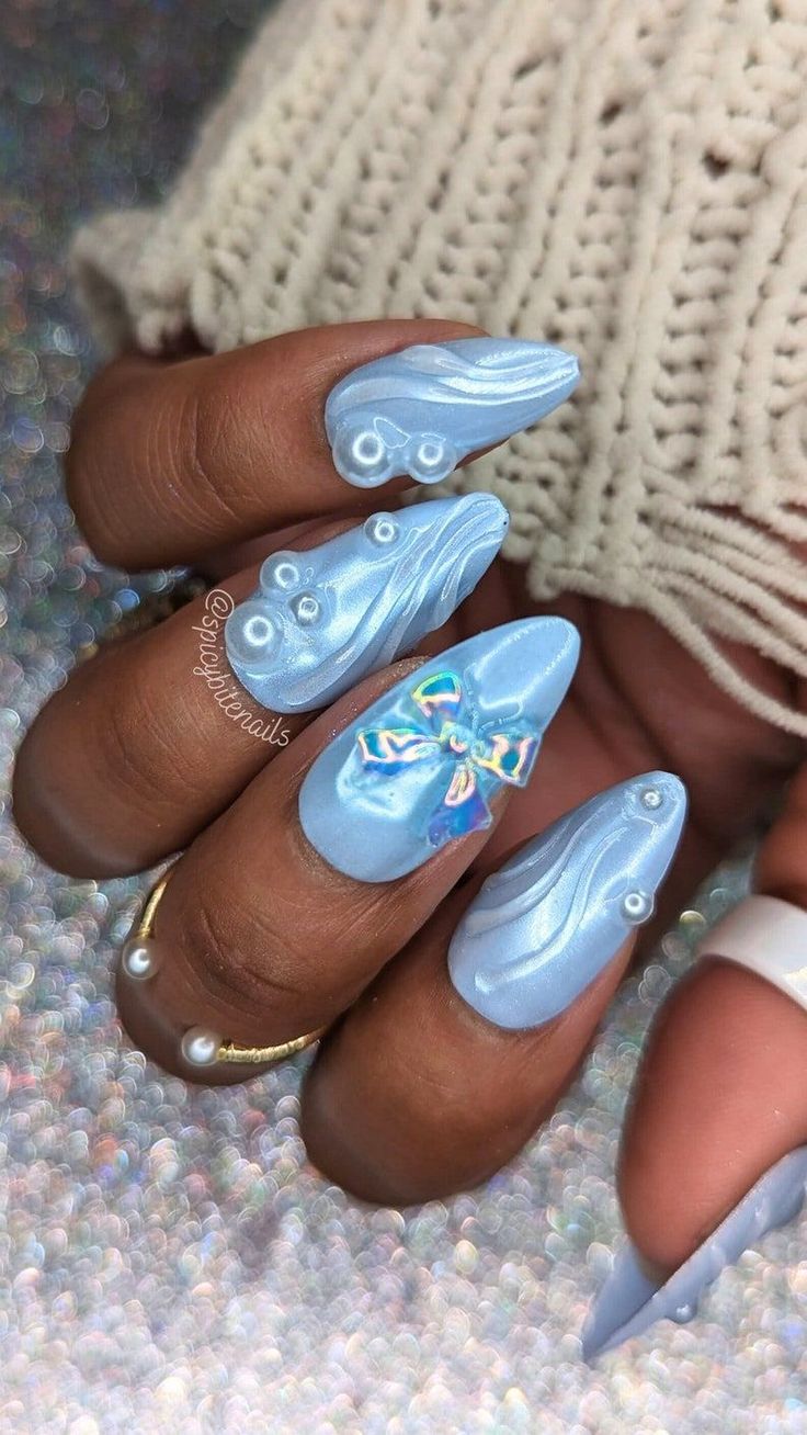 Chic Elegant Blue Nail Design with Glossy Finish, Intricate Patterns, and Playful Bow Embellishment.