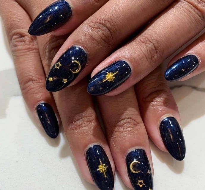 Whimsical Celestial Nail Design: Deep Navy Base with Gold Accents and Cosmic Motifs.