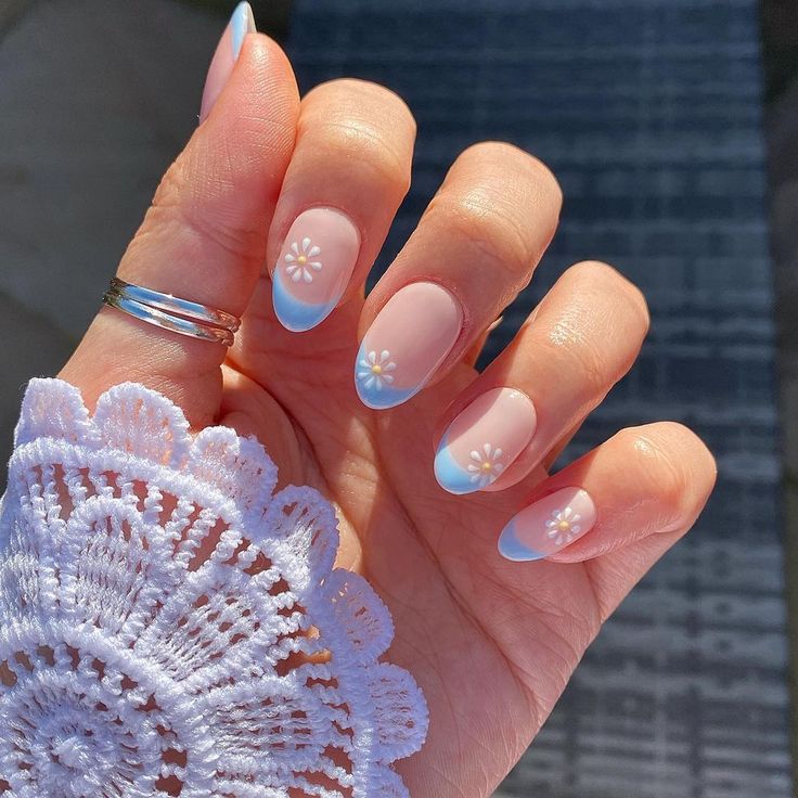 Charming Spring-Inspired Nail Design: Soft Nude Base with Delicate Blue French Tips and Whimsical White Florals.