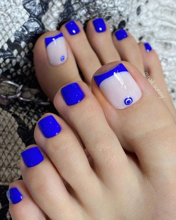 Chic Vibrant Blue Toenail Design with Artistic Evil Eye Motif and Accented Colors.