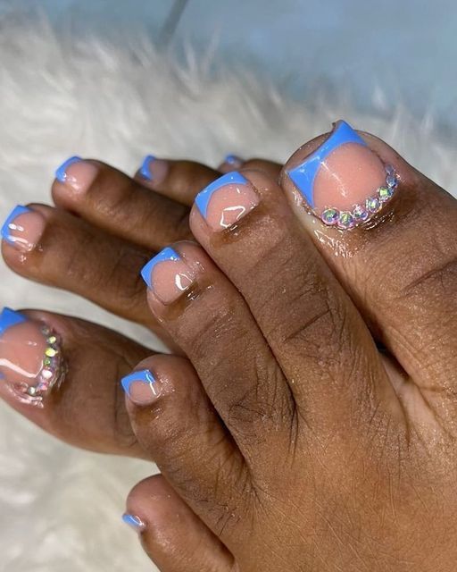 Chic Summer Toe Nail Design: Nude Base with Striking Blue Tips and Glamorous Rhinestones.