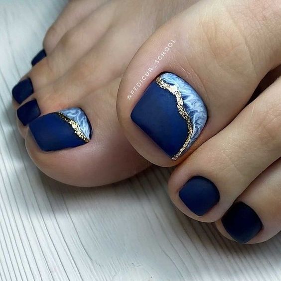 Sophisticated Navy Blue Pedicure with Marbled Accents and Chic Gold Stripes.