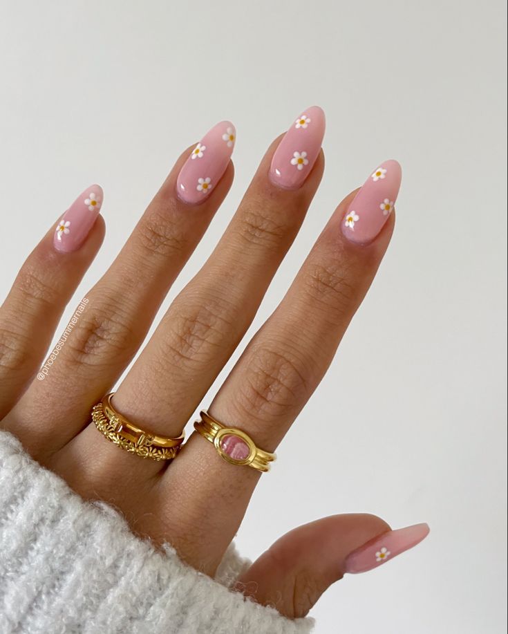 Elegant Pink Nails with White Flowers and Gold Rings for a Whimsical Spring Look.