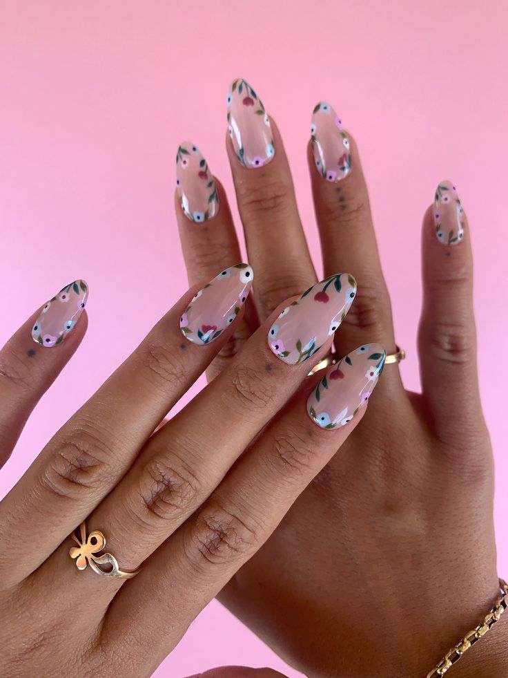 Whimsical Floral Nail Design with Elegant Elongated Clear Tips and Soft Pink Background.