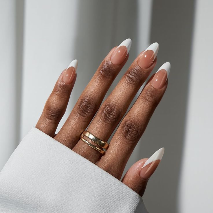 Chic Almond-Shaped Nails with Nude Base and White Tips, Perfectly Enhanced by Gold Rings.