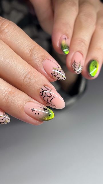 Playful Halloween Nail Design: Soft Pink with Vibrant Green Accents and Whimsical Spiderweb Patterns.