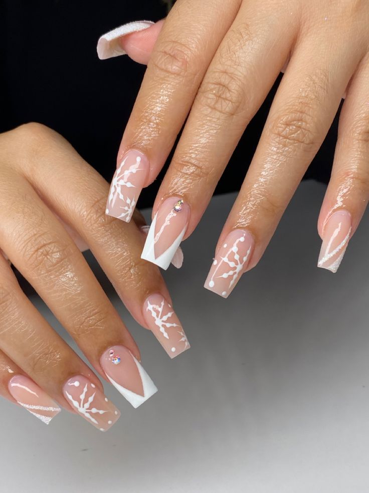 Sophisticated Nail Design: Soft Nude and Crisp White with Artistic Branches and Modern Shapes.