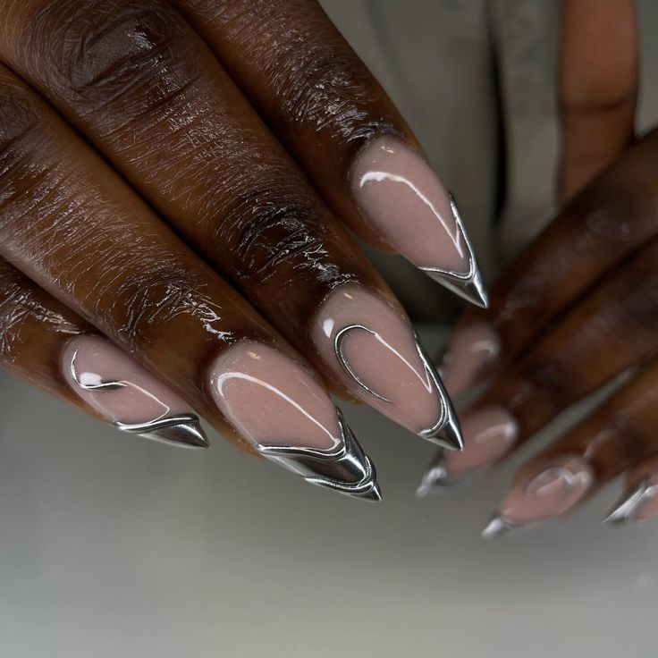 Sleek Stiletto Nails: Glossy Nude Base with Edgy Metallic Silver Tips and Intricate Lines for Sophisticated Flair.