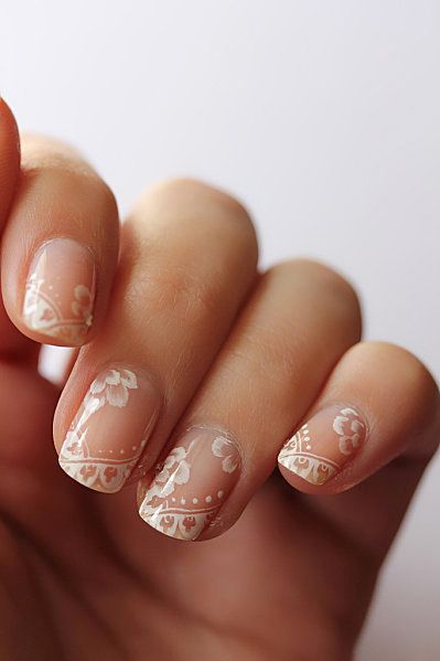 Elegant Floral Nail Design with Intricate White Patterns on a Soft Nude Base.