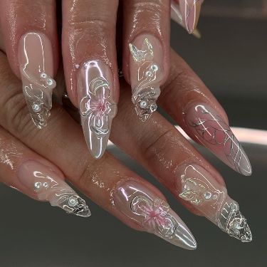 Elegant Stiletto Nail Design with Floral Embellishments and Pearls for a Modern Feminine Aesthetic.