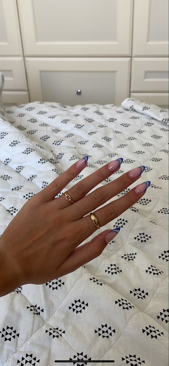 Chic Oval Nail Design: Soft Nude Base with Vibrant Blue Tips and Delicate Rings.