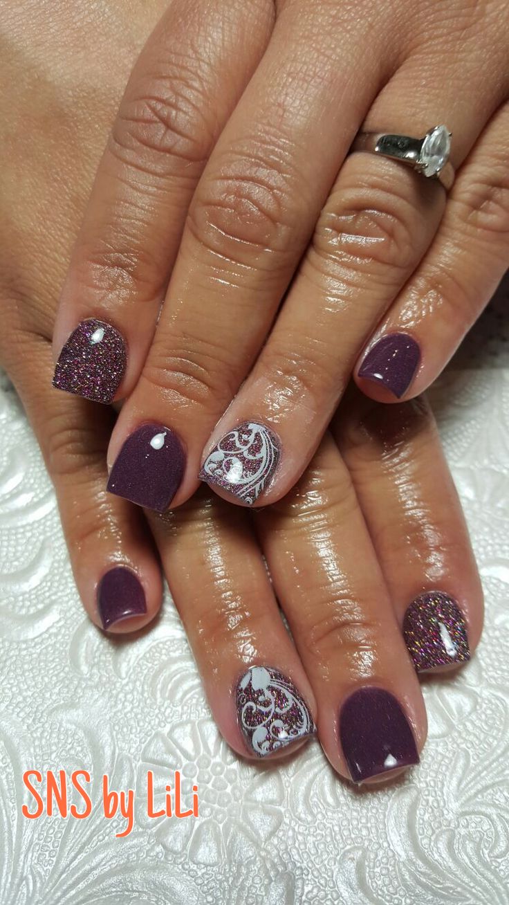 Sophisticated Plum and Glitter Nail Design with Intricate White Patterns.