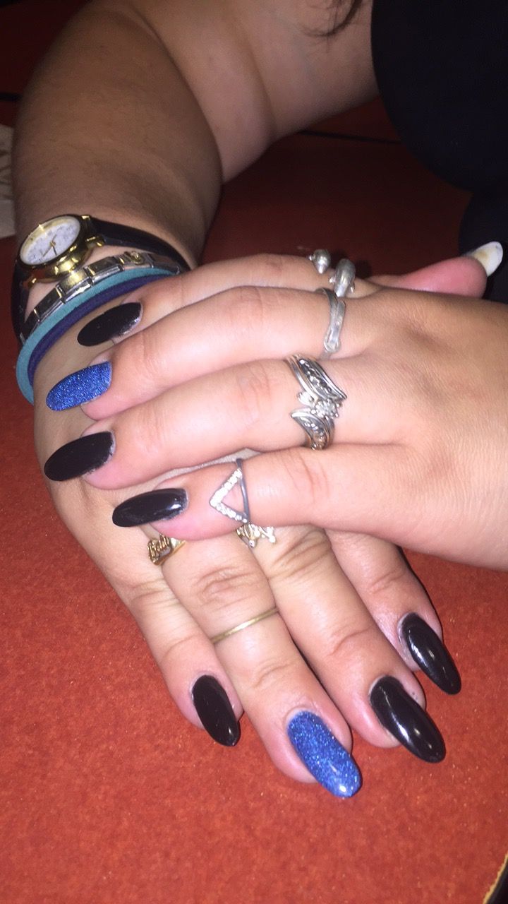 Chic Elongated Nail Design: Glossy Black and Vibrant Blue Glitter Elegance with Ring Accents.